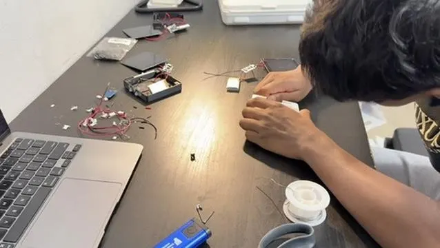 A student intern soldering light electronics in the workshop